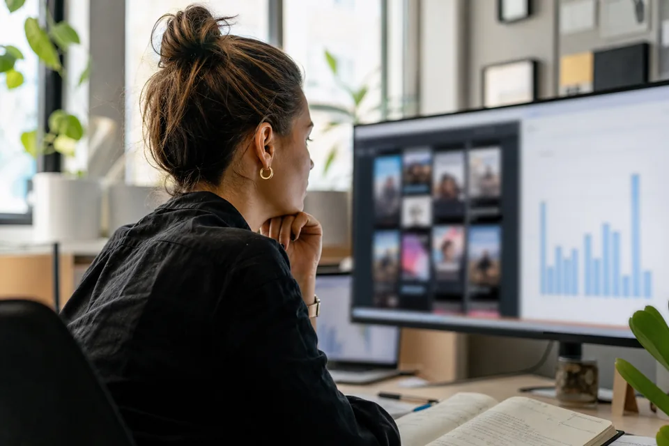 Agency media buyer reviewing short video ad variants and their cost per purchase on a large monitor